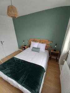 1 dormitorio con 1 cama grande y pared verde en Chambre dans maison, en Baillet-en-France