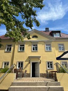 ein gelbes Haus mit Treppen, die zu ihm führen in der Unterkunft Hotel Zum Pfeiffer in Radebeul