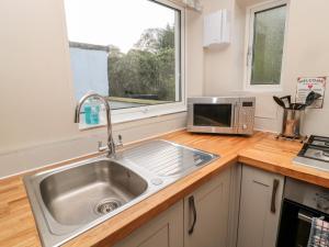 eine Küche mit einer Spüle und einer Mikrowelle in der Unterkunft The Anchorage in Alnwick
