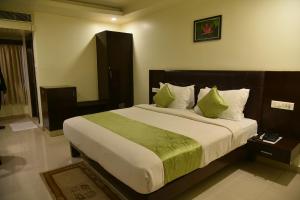 a bedroom with a large bed with green sheets and pillows at Hotel green apple in Visakhapatnam