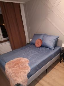 - un lit avec un oreiller orange et un drap bleu dans l'établissement Apartament przy Uniwersytecie Kopcińskiego 15, à Łódź