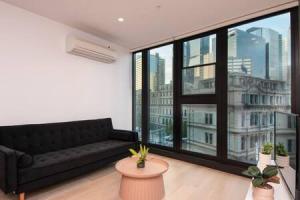 a living room with a black couch and a large window at Stunning 2BR Apt nr Yarra City view Free parking in Melbourne