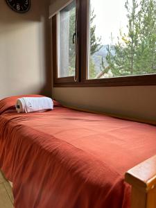 1 cama con manta roja y ventana en RETAMA en San Carlos de Bariloche