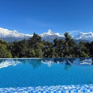 a swimming pool with mountains in the background at Himalayan Deurali Resort in Pokhara