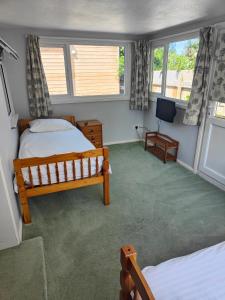 a bedroom with two beds and a flat screen tv at Pine Lodge in Newquay