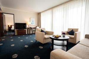 a hotel room with a couch and chairs and a television at Hotel Vier Jahreszeiten Starnberg in Starnberg