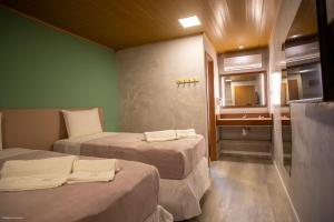 a room with two beds and a bathroom with a mirror at Bella Rosa Noronha in Fernando de Noronha