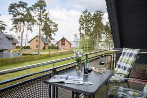 een tafel met wijnglazen en bloemen op een balkon bij Ferienwohnung Biber im Müritz Seepark in Marienfelde