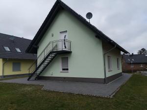 een wit huis met een trap aan de zijkant bij Ferienwohnung Biber im Müritz Seepark in Marienfelde