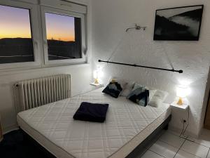 - une chambre avec un lit blanc et 2 lampes dans l'établissement Appartement sur les hauteurs de Gérardmer, à Gérardmer