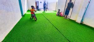een jonge jongen die fietst op een groene vloer bij Studio at Kisimani Heights Apartment. in Mombasa