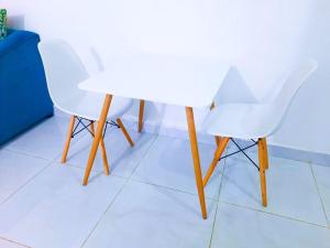 twee witte stoelen en een witte tafel op een tegelvloer bij Studio at Kisimani Heights Apartment. in Mombasa