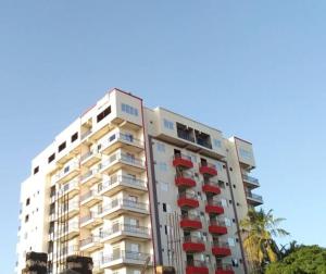 een hoog wit gebouw met rode balkons en palmbomen bij Studio at Kisimani Heights Apartment. in Mombasa