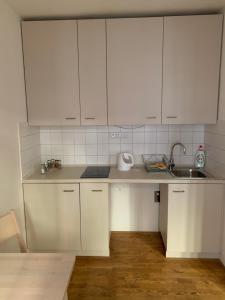 a white kitchen with a sink and white cabinets at Mitte Apartments in Brno