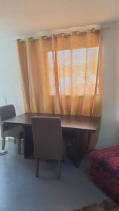 uma mesa com cadeiras e uma janela com uma cortina em Apartamento em betim em Betim