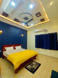 a bedroom with a yellow bed and a blue wall at Little Dream Homestay Hampi in Hampi