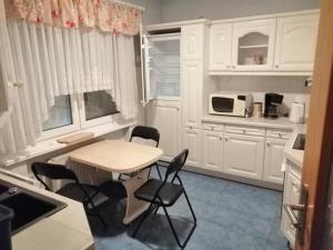 eine Küche mit weißen Schränken sowie einem Tisch und Stühlen in der Unterkunft Ferienhaus Residenz Wismar - ABC430 in Wismar