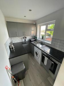 uma pequena cozinha com um lavatório e uma máquina de lavar roupa em Lovely 1 bedroom flat. Parking & Garage. Sky TV & Broadband em Colchester
