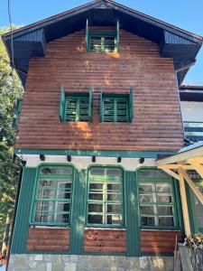 a house with green shuttered windows on top of it at Villa Adis with Hot Jacuzzi & Sauna in Borovets