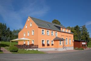 een groot oranje gebouw met een zwart dak bij Wolfsgrunder Festhof in Dorfchemnitz