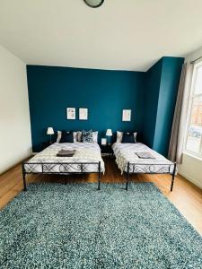 1 dormitorio con 2 camas y pared azul en Jubilee Rooms 15 Minutes Central London en Londres