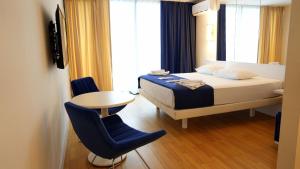 Lux Apart Hotel 555 في باتومي: غرفة نوم بسرير وطاولة وكرسي