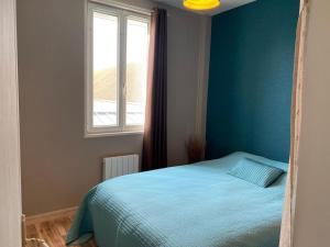 een blauwe slaapkamer met een bed en een raam bij La Ptit Sophie - Conciergerie Leroy in Boulogne-sur-Mer