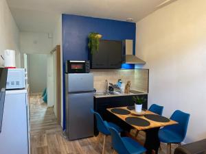 een keuken met een tafel en blauwe stoelen en een koelkast bij La Ptit Sophie - Conciergerie Leroy in Boulogne-sur-Mer