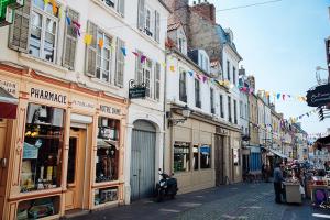 een straat met gebouwen en vlaggen en een straat met winkels bij La Ptit Sophie - Conciergerie Leroy in Boulogne-sur-Mer