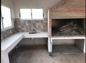 a kitchen with a sink and a fireplace at Casa de Coral in Punta Del Diablo