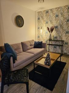 a living room with a couch and a clock on the wall at Apartamenty "Hubertówka" 