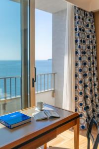a table with a book and a cup on it with a window at Hotel Royal Continental in Naples