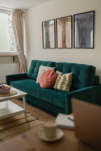 zieloną kanapę z poduszkami w salonie w obiekcie Apartament Zakątek Kudowa Przytulny w Kudowie Zdroju