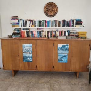 einem Holzschrank mit Büchern an der Wand in der Unterkunft Dolphin Inn Guesthouse & Apartments in Christchurch