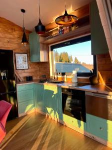 a kitchen with green cabinets and a large window at Mokki - A-frame cozy în Apuseni in Mărişel