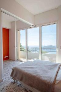 - une chambre blanche avec de grandes fenêtres et un lit dans l'établissement Appartement spacieux - Vue mer panoramique, à Villefranche-sur-Mer