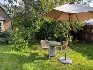 uma mesa e cadeiras debaixo de um guarda-sol num quintal em Braemorriston Lodge em Elgin