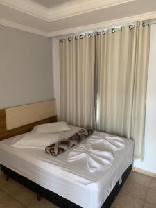 a bedroom with a white bed with a window at Hotel Turístico de Alagoinhas in Alagoinhas