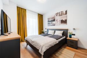a bedroom with a bed and a desk and a television at Smart Home - Gloria Apartment by Avenue in Timişoara
