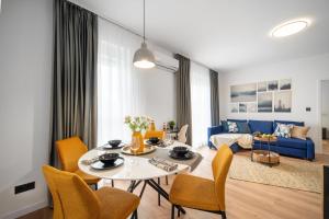 ein Wohnzimmer mit einem Tisch, Stühlen und einem blauen Sofa in der Unterkunft Smart Home - Gloria Apartment by Avenue in Timişoara