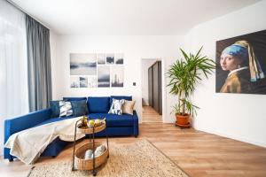 a living room with a blue couch and a painting at Smart Home - Gloria Apartment by Avenue in Timişoara
