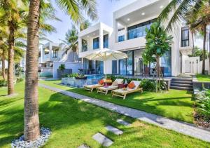 a large white house with palm trees in front of it at Vacation Home Ocean Villas in Da Nang