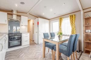 eine Küche mit einem Esstisch und blauen Stühlen in der Unterkunft Maison Verte Lodge 8 Close to St Andrews in Strathkinness