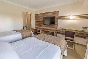 a hotel room with two beds and a flat screen tv at Hotel Village Premium Campina Grande in Campina Grande