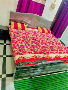 a bed with a red blanket with flowers on it at Radhey Krishna home stay in Mathura