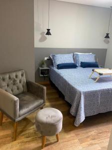 um quarto com uma cama e uma cadeira em Apartamento Flat Palladium em São Vicente