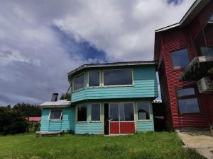 ein blaues Haus neben einem roten Haus in der Unterkunft CASA CON QUINCHO in Ancud