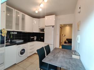 a kitchen with white cabinets and a table with chairs at Maestro II Apartment in Larnaka +2 photos