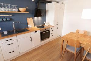 a kitchen with white cabinets and a wooden table at NEU! Ferienhaus Kleine Auszeit - Nur für Feriengäste - ABC1 in Wismar