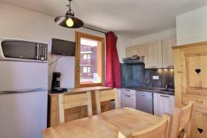 eine Küche mit einem Tisch und einem Kühlschrank in der Unterkunft Cimes 2 B17 in Méribel